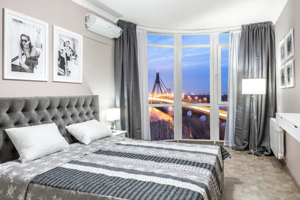 A contemporary bedroom interior with a view of a bridge at twilight.